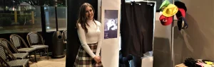 Woman smiling beside a cheap photobooth hire setup with props at an event in Sydney
